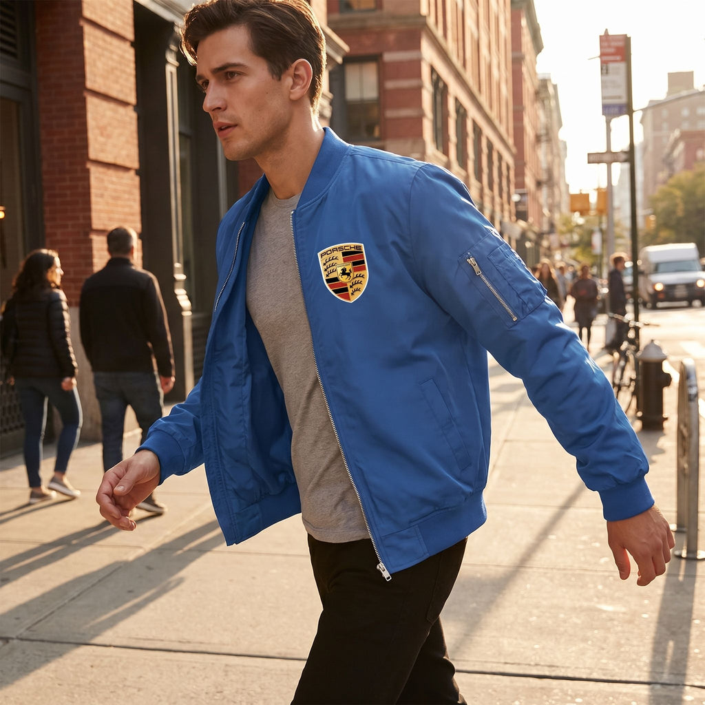 Dynamic city sidewalk scene capturing a male model in Porsche varsity jacket mid-motion, demonstrating its windbreaker features and functional pockets.