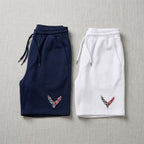 Flat-lay of men's Chevrolet Corvette fleece shorts in navy and white on textured fabric background.