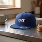 Side profile of small Cadillac Car Snapback Hat on sleek metallic countertop in a minimalist kitchen under natural light.