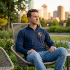 Casual scene of a male model wearing Porsche lightweight athletic shirt sitting outdoors in an urban park during golden hour, emphasizing versatility and athletic fit.