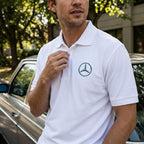Male model adjusting Mercedes-Benz polo collar outdoors, capturing natural fit, stitching detail, and lifestyle scene.