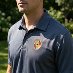 Close-up of men's Porsche polyester polo showing smooth fabric, reinforced stitching, and tagless collar under natural sunlight.