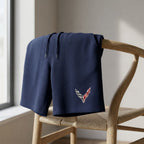 Close-up of men's Chevrolet Corvette athletic fleece shorts draped over a wooden chair, highlighting the breathable fabric and soft weave in natural daylight.