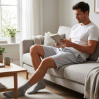 Casually dressed man relaxing at home on a plush sofa wearing men's Chevrolet Corvette fleece shorts, emphasizing softness and breathability.