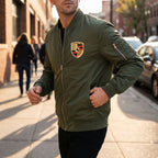 Model in motion wearing men's lightweight bomber jacket during golden hour on city sidewalk.