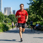 Man jogging in city park wearing navy men's Porsche polyester polo, highlighting athletic fit and moisture-wicking qualities in motion.
