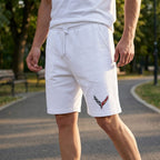 Close-up of male model in white Chevrolet Corvette fleece shorts in an urban park during early morning, emphasizing fabric texture and casual style.