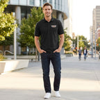 Full-body shot of a male model in black Cadillac Car Dry Blend Polo in outdoor setting, showing classic fit, structured silhouette, and neat finish.