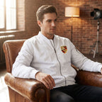 Indoor shot of male model in Porsche bomber jacket seated on leather armchair in studio.