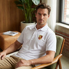 Indoor scene with man seated in modern lounge wearing Porsche Dry Blend Polo, focusing on fit, collar, and soft lighting details.