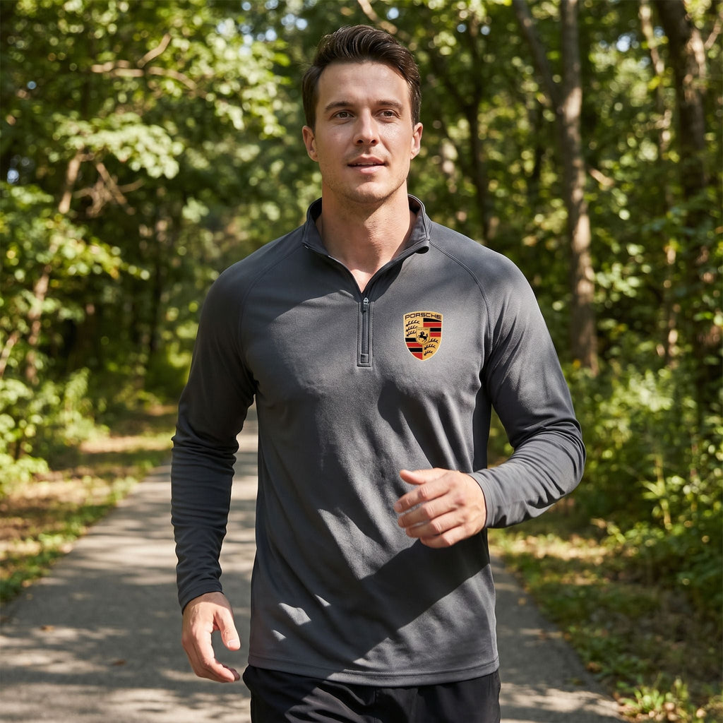 Model wearing men's dark gray quarter-zip athletic shirt outdoors, demonstrating flexibility and modern fit.