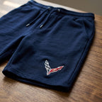 Close-up of men's Chevrolet Corvette fleece shorts showing high-quality fabric, texture, and stretch on a wooden surface with soft natural light.