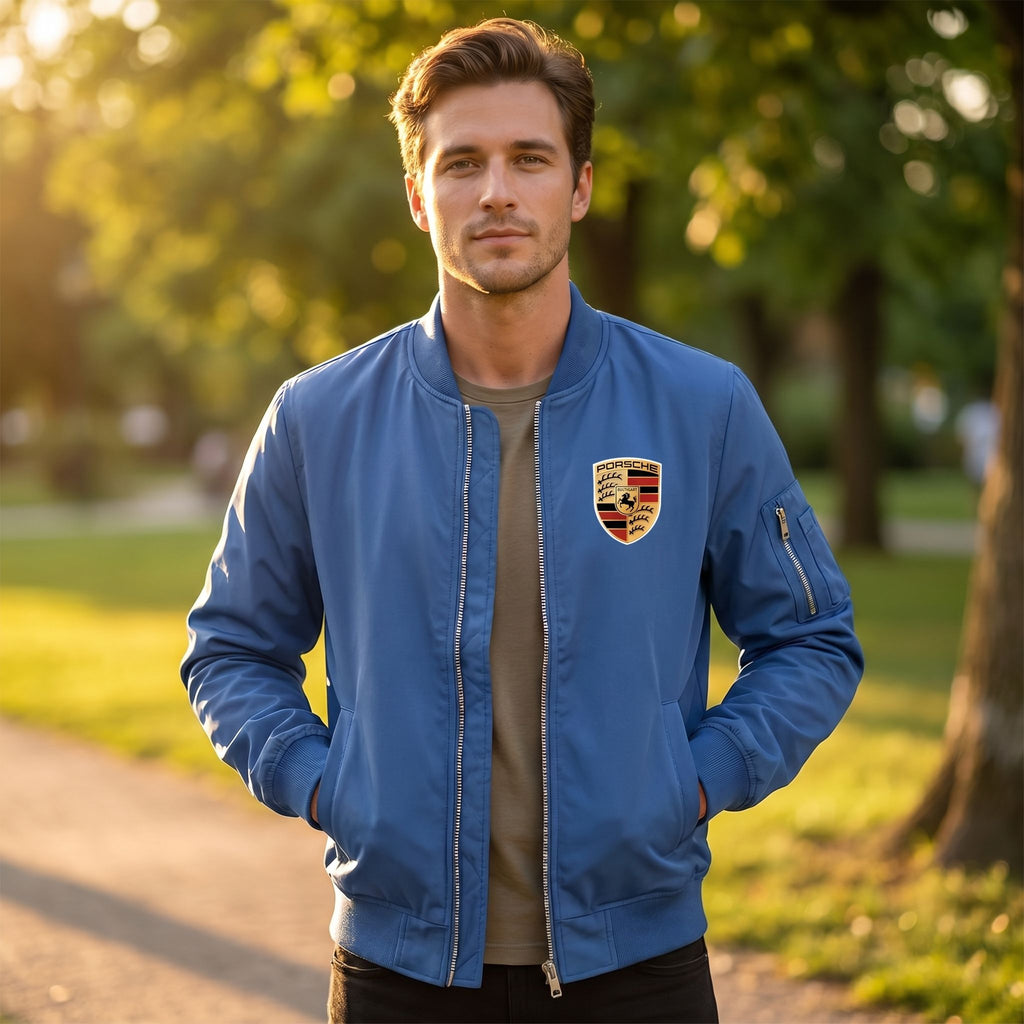 Male model wearing Porsche lightweight windbreaker in a park at sunset, showcasing its minimalist design and breathable softshell fabric with natural outdoor scenery.