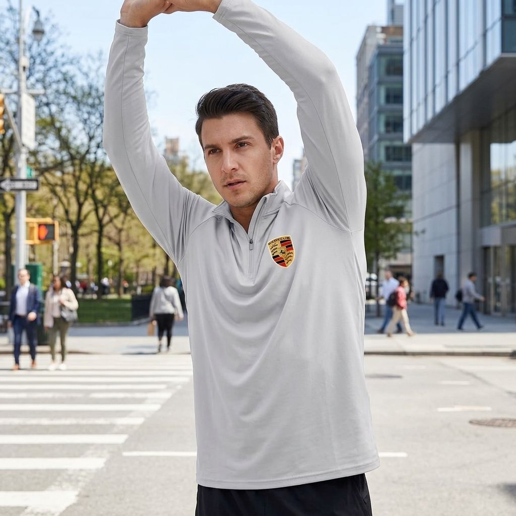 Male model in urban setting wearing Porsche athletic shirt, mid-motion, showcasing sporty cut, breathable fabric, and modern style.