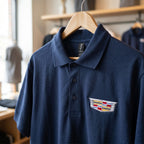 Close-up of Men's Cadillac Car Dry Blend Polo showing textured cotton-polyester knit fabric, welt collar, and dyed-to-match buttons.