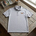 Flat lay of men's Cadillac Polo on rustic wooden table showing fabric, collar, and cuffs.