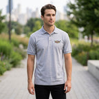 Full-body of male model wearing Cadillac Polo in urban park setting highlighting fit and fabric sheen.