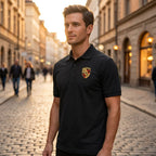 Male model in black Porsche Car Dry Blend Polo standing outdoors during golden hour, emphasizing fabric sheen and structured fit with city background.