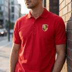 Male model wearing Porsche Car Dry Blend Polo outdoors against a brick wall, emphasizing fit, structure, and moisture-wicking fabric in natural sunlight.