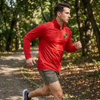Man running in park wearing Porsche athletic shirt, emphasizing fabric movement and moisture-wicking features.