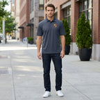 Full-body of male model wearing navy Porsche polyester polo outdoors in an urban setting, showcasing athletic fit and fabric drape.