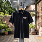 Full-body view of men's Cadillac Car Dry Blend Polo hanging on outdoor wooden hook, showcasing relaxed fit, classic style, and natural outdoor background.