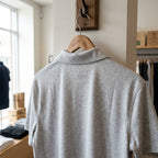 Back view of men's Mercedes-Benz polo hanging in retail with focus on seamless collar, clean lines, and natural fabric creases.