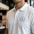 Close-up of men's Mercedes-Benz dry blend polo highlighting collar, buttons, and fabric texture in natural indoor light.