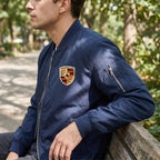 Side view of male model in Porsche softshell jacket sitting on park bench, showing ribbed collar, cuffs, hem, and fabric texture in natural daylight.