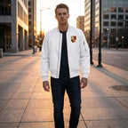 Full-body view of male model wearing Porsche bomber jacket on city sidewalk with sunset glow.