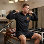 Male athlete in gym locker room putting on men's Porsche athletic shirt, highlighting fit and stretch of the fabric.