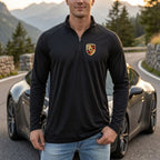 Flat lay of men's Porsche quarter-zip athletic shirt on neutral surface, showcasing zipper detail and technical fabric.