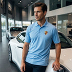 Male model wearing white Porsche polyester polo leaning against a luxury car in a sleek showroom, highlighting the polish and fit of the fabric.