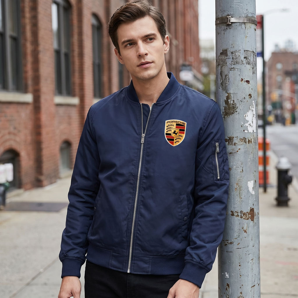 Male model in Porsche bomber jacket in urban setting during overcast weather, focusing on subtle textures, zipper, and casual style.