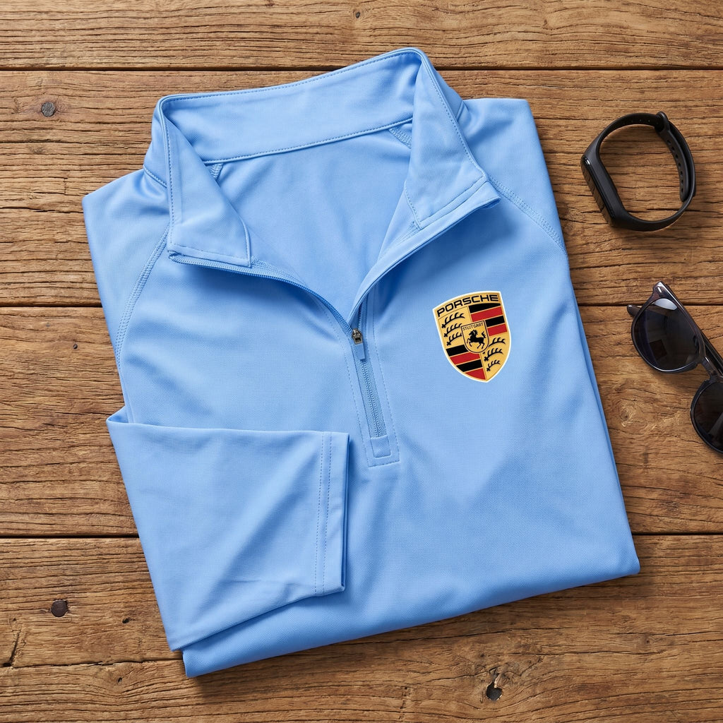 Flat-lay of neatly folded Porsche quarter-zip shirt with accessories, showing breathable material and design features.