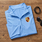 Flat-lay of neatly folded Porsche quarter-zip shirt with accessories, showing breathable material and design features.