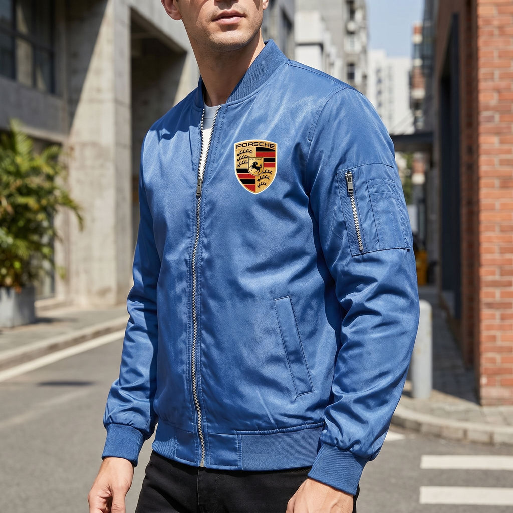 Men's Porsche lightweight bomber jacket displayed on a model in an urban street scene highlighting its softshell fabric, structured details, and modern style.