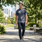 Candid outdoor shot of man in navy Porsche polyester polo walking in a park, showcasing fit and breathable fabric in natural environment.