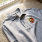 Overhead shot of Porsche Car Dry Blend Polo draped on woven fabric, emphasizing the front fabric details and collar with natural lighting.
