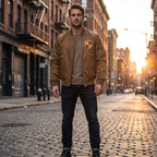 Full-body view of man wearing Porsche bomber jacket in urban street during golden hour, highlighting its modern design.