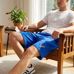 Model seated in a lounge wearing men's lightweight fleece shorts, showcasing comfort, stretch, and versatile fit with natural sunlight.