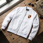 Flat-lay of men's Porsche bomber jacket with sunglasses and backpack on wooden surface.