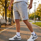 Model strolling in an urban park during golden hour in men's Chevrolet Corvette fleece shorts, showing fit, comfort, and everyday style.