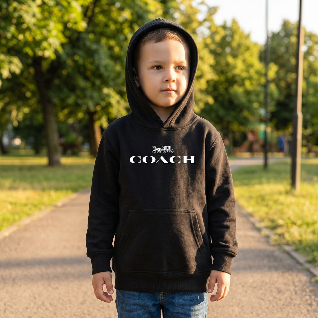 Full-body of a child wearing youth kids coach pullover hoodie in a park, showing relaxed fit and textured fabric in a sunny outdoor setting.